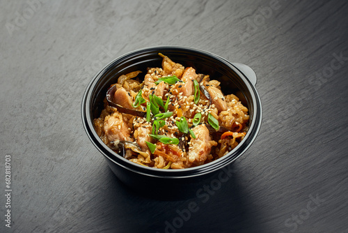 Traditional Asian dish, chicken or pork with rice and mushrooms in a plastic bowl photo