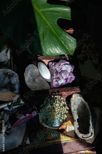 scene showing a table with gemstones in a wooden box , incense stick smoking and a monstera plant for meditation and calm aesthetic