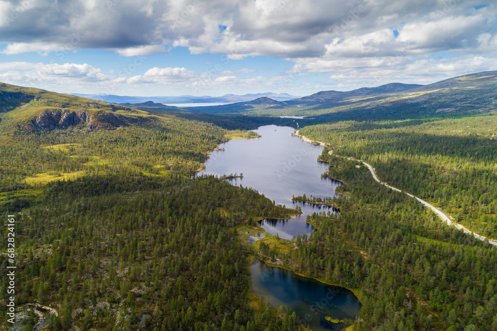 Aerial high angle view of river and road running through forest and mountainous landscape in northern Sweden