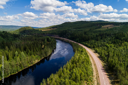 Aerial high angle view of river and road running through forest and mountainous landscape in northern Sweden