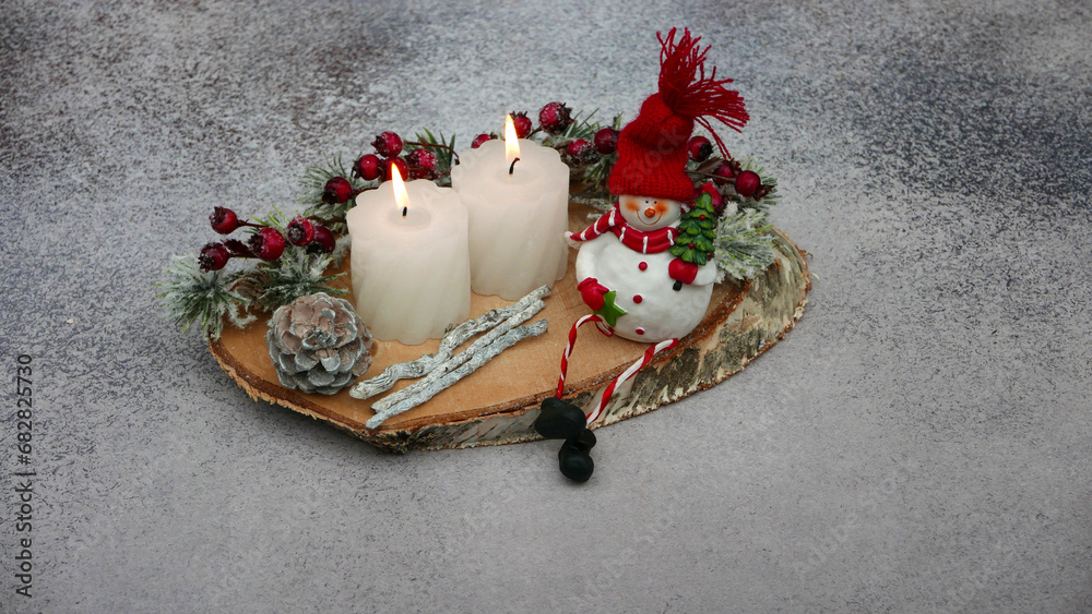 Φωτογραφία Advents und Weihnachtsdekoration: Kerzen, Zweige und lustiger Schneemann auf einer Baumscheibe arrangiert