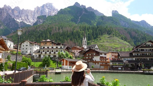 Woman enjoying Alleghe village view in the foothills of green valley of Dolomites photo