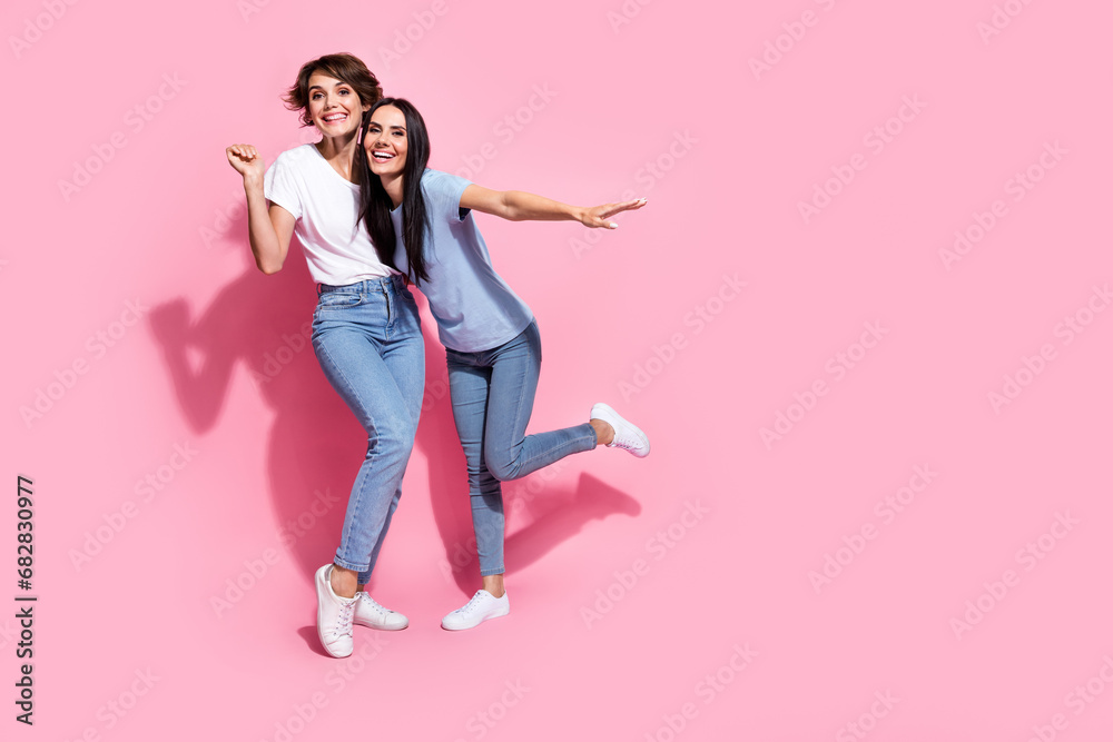 Full body cadre of two funny women dance together wear denim jeans t shirt trendy apparel black friday ad isolated on pink color background Full body cadre of two funny women dance together wear denim jeans t shirt trendy apparel black friday ad isolated on pink color background