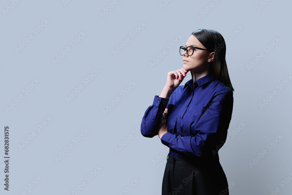 Profile view, portrait of serious young woman in on grey background, copy space Profile view, portrait of serious young woman in on grey background, copy space
