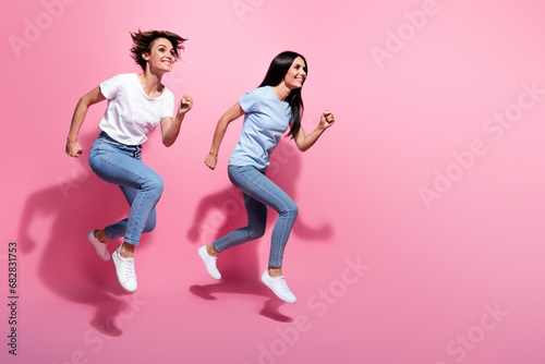 Full body photo of two running funky women have fun fast speed last chance buy clothes discount advert isolated on pink color background