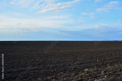 plowed agricultural field with cloudscape on background 