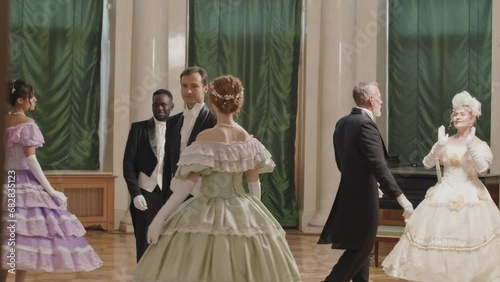 Full length shot of multiracial people in charming Victorian style dresses dancing with each other at glamorous debutante ball photo