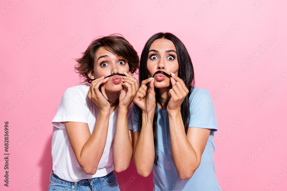 Photo portrait of two joke funky lady brunette hair best friends forever playing hair mustache blow lips isolated on pink color background Photo portrait of two joke funky lady brunette hair best friends forever playing hair mustache blow lips isolated on pink color background