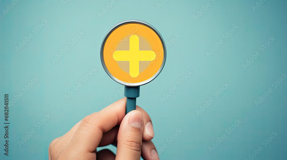 Hand holding magnifier glass with yellow plus sign symbol inside for focus healthcare insurance and offer positive thinking mindset of personal development concept. blue background Hand holding magnifier glass with yellow plus sign symbol inside for focus healthcare insurance and offer positive thinking mindset of personal development concept. blue background