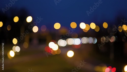 Lights from cars moving on a road at night, out of focus.