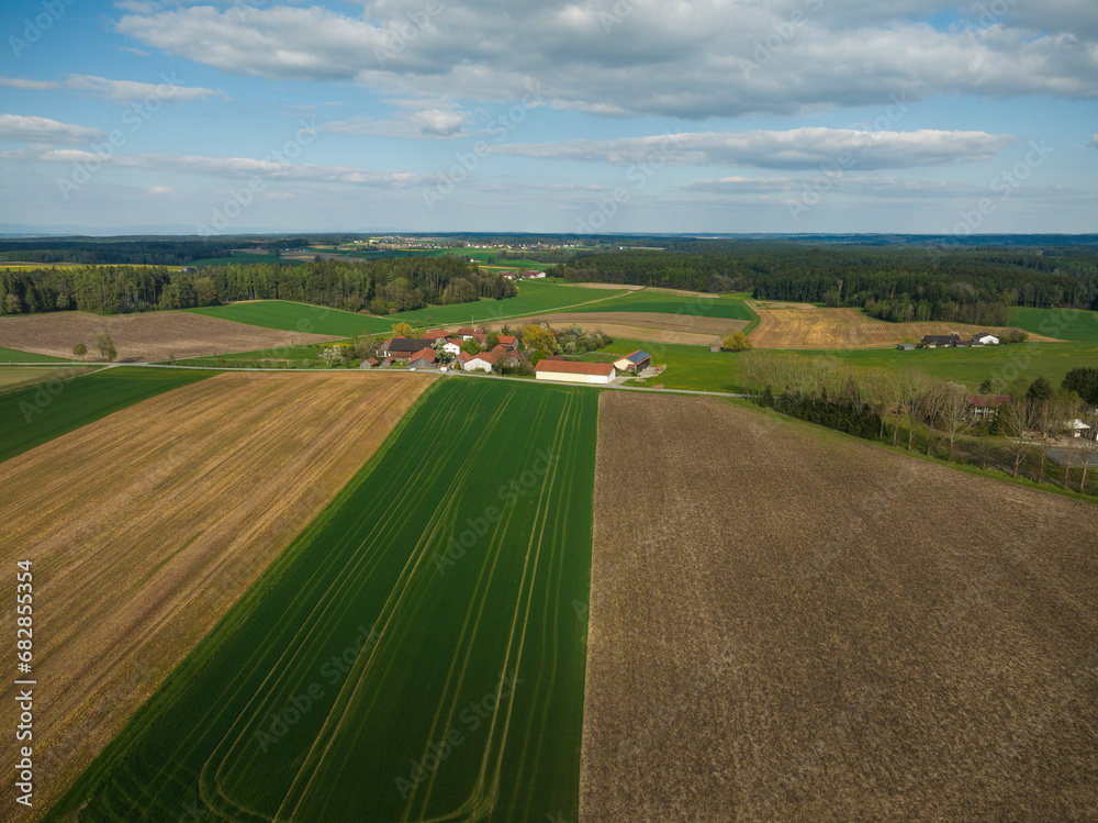 Drone image of rural landscape with different colored crops and forests. Bavaria, Germany