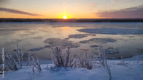 Sunrise over the frozen river in winter