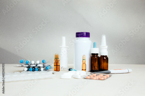 A set of medicines for treatment in bottles and tablets in transparent plates on a light background. Front view