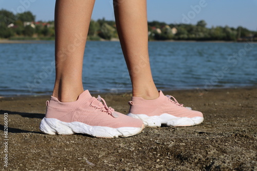 Female legs in pink sneakers, outdoor.
