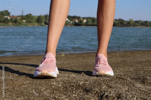 Female legs in pink sneakers, outdoor.