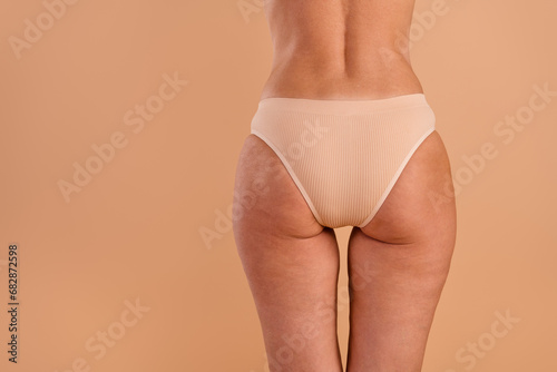 Back rear view photo of young woman hips buttocks anti cellulite massage product surgery empty space isolated on beige color background