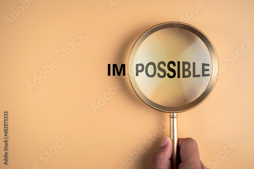 Magnifying glass in hanh focus on possible text and not focus impossible word. Believe in hope to success business form education by yourself positive think motivational inspirational concept.