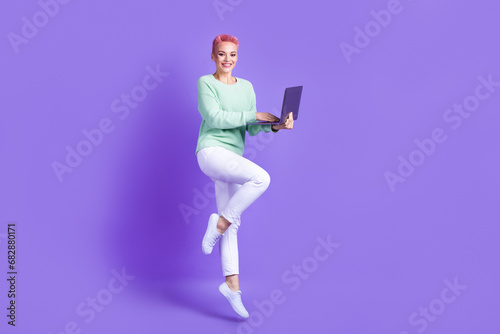 Full length photo of sweet shiny girl wear turquoise sweater jumping working device empty space isolated violet color background © deagreez