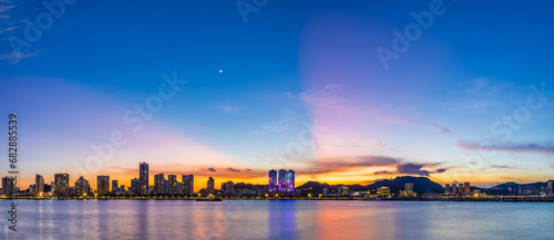Beautiful coastline and modern building scenery at sunset by the sea, Zhuhai, Guangdong Province, China.