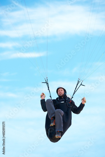 Man, parachute and paragliding in air nature for exercise, healthy adventure with extreme sport. Athlete, glide or fearless for outdoor fitness for health wellness, helmet or safety gear by blue sky