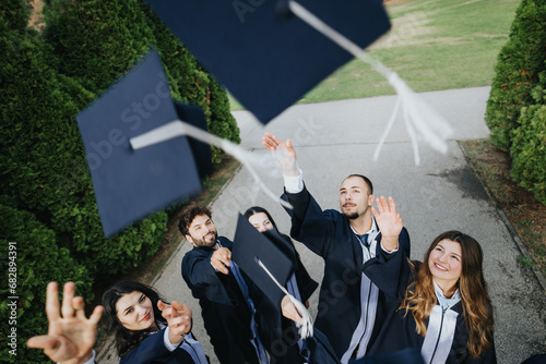 Young graduates celebrate in a park, throwing caps and congratulating each other for achieving college milestones.