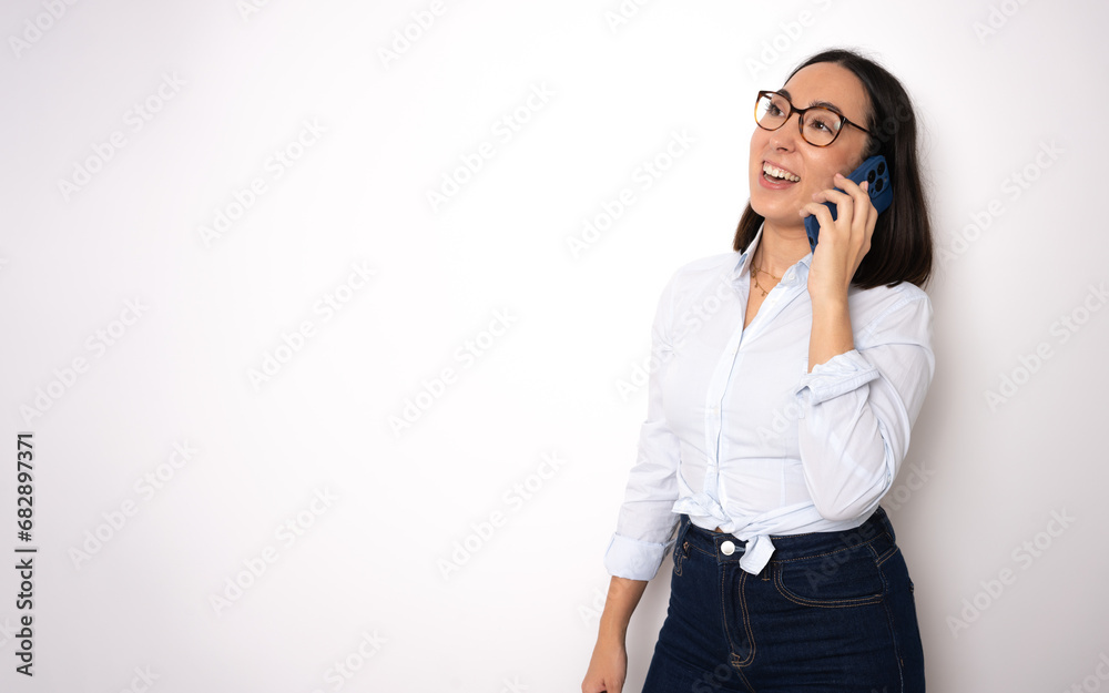 Cheerful attractive young businesswoman in glasses standing and using mobile phone over white background Cheerful attractive young businesswoman in glasses standing and using mobile phone over white background