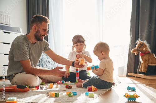 Construction toys. Father is playing with two little boys on the floor photo