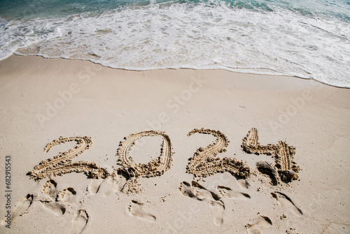 2024 written in white sand on tropical beach, happy New Year