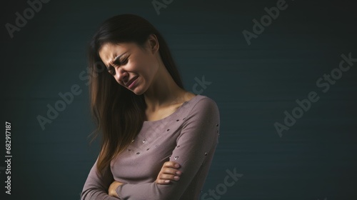 Photo, a woman in a plain studio, wincing as she touches her sore back, the unembellished surroundings highlighting the genuine discomfort