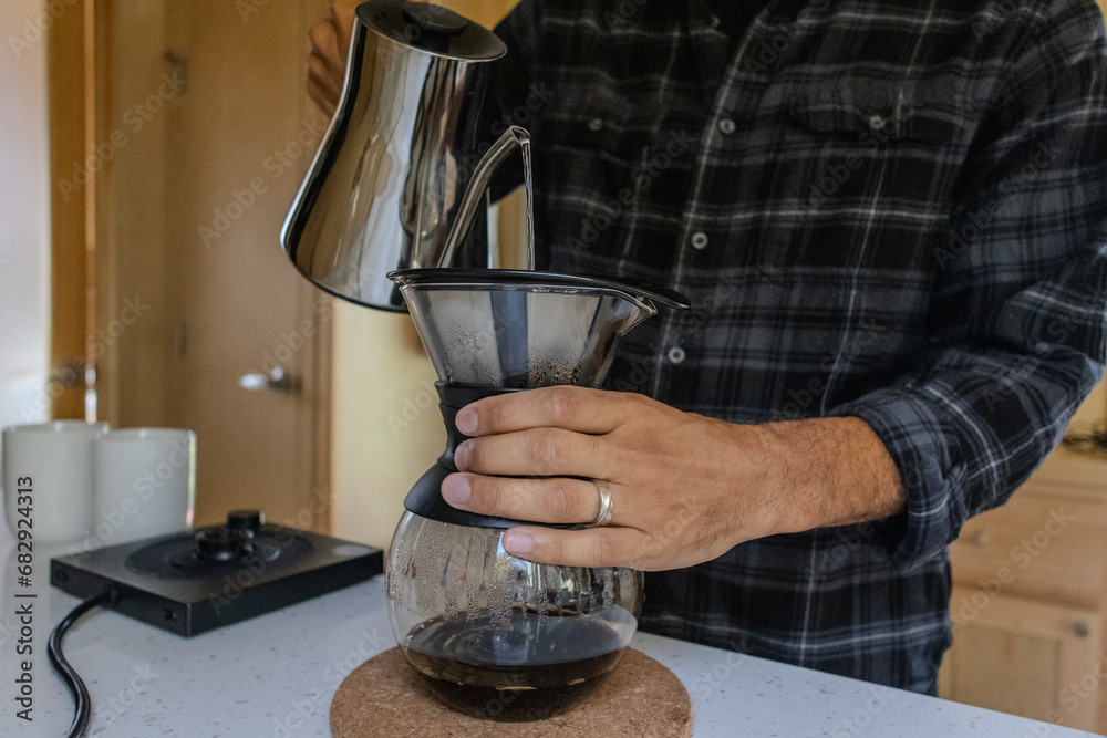 Man making pour over coffee in wood cabin home