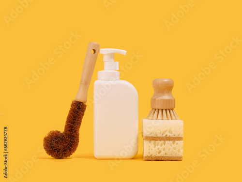 Washing dishes in the kitchen with eco friendly sponges and brushes. White dishwashing gel dispenser.