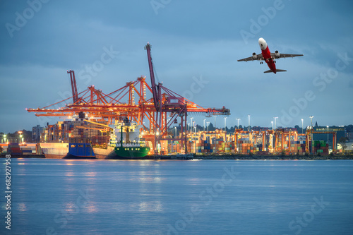 International cargo ship with logistics and containers cargo illumination, gantry cranes and commercial airplane flying at habour photo