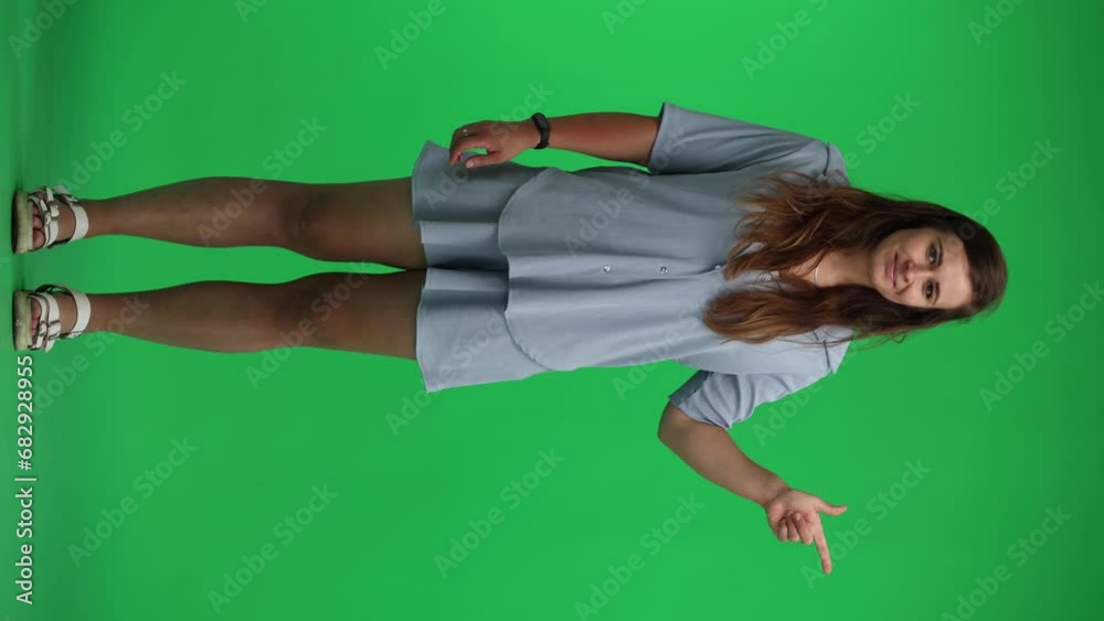 woman on a green background. points with a finger in full growth woman on a green background. points with a finger in full growth