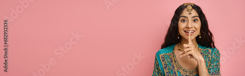 Bild auf Leinwand jolly indian woman in traditional costume showing silence gesture and looking at