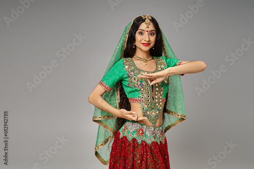 attractive young indian woman with bindi dot posing with hands in front of her and looking at camera