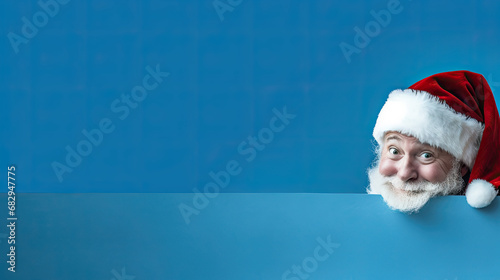 Santa Claus peeking around a corner, blue background, place for a text 