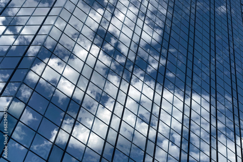 Close up of a modern glass office building. Reflection of the sky with clouds in the glass of the building.