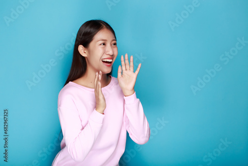 Shouting with mouth wide open, friendly young woman, Asian woman with open mouths raising hands screaming announcement isolated on blue background, Portrait woman shouting over blue background