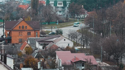 Real time of suburban life. Passing cars and walking pedestrians. Multi-colored roofs of houses and municipal roads. Winter atmosphere.