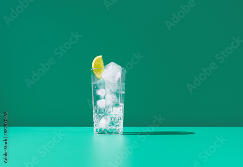 Refreshing gin tonic in a glass with ice on green background photo