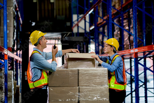 Male and female workers in safety clothing wrap parcels in a factory warehouse. Logistics and export business concept. engineer working in warehouse