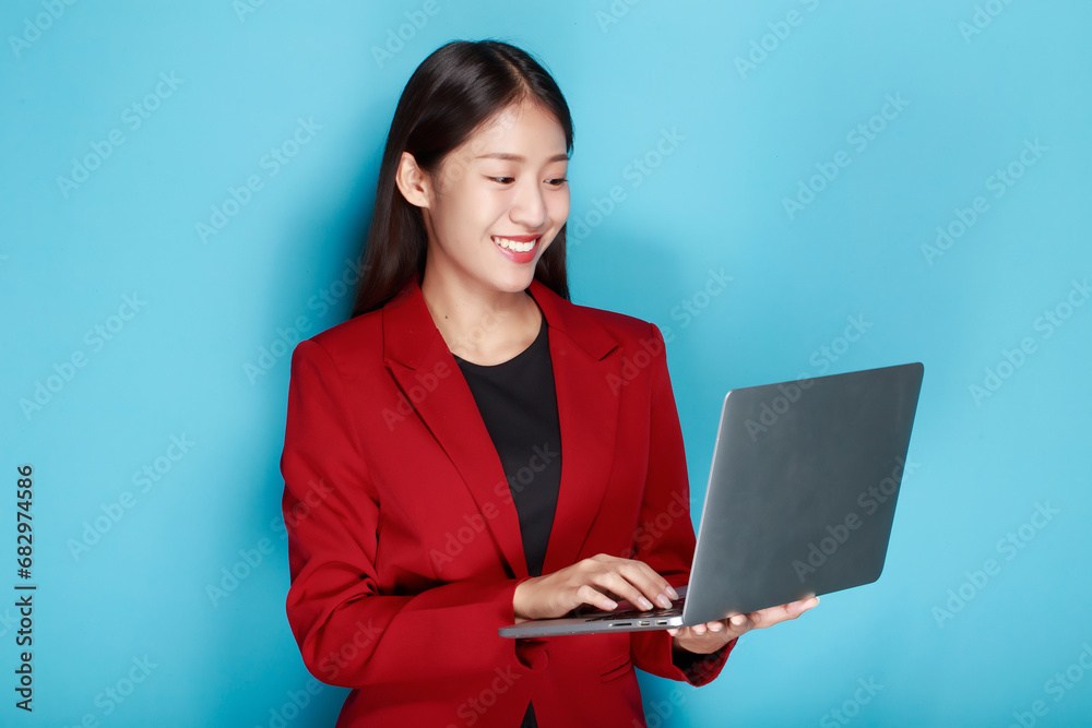 Portrait of a happy asian businesswoman working on laptop computer isolated over blue background Portrait of a happy asian businesswoman working on laptop computer isolated over blue background