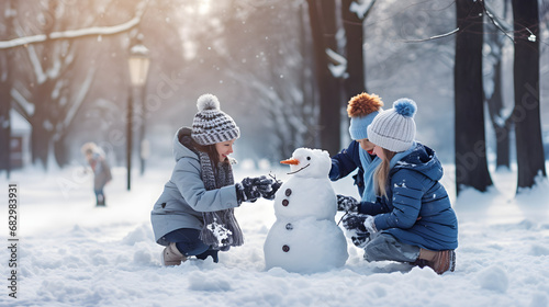 Children building snowman in winter park