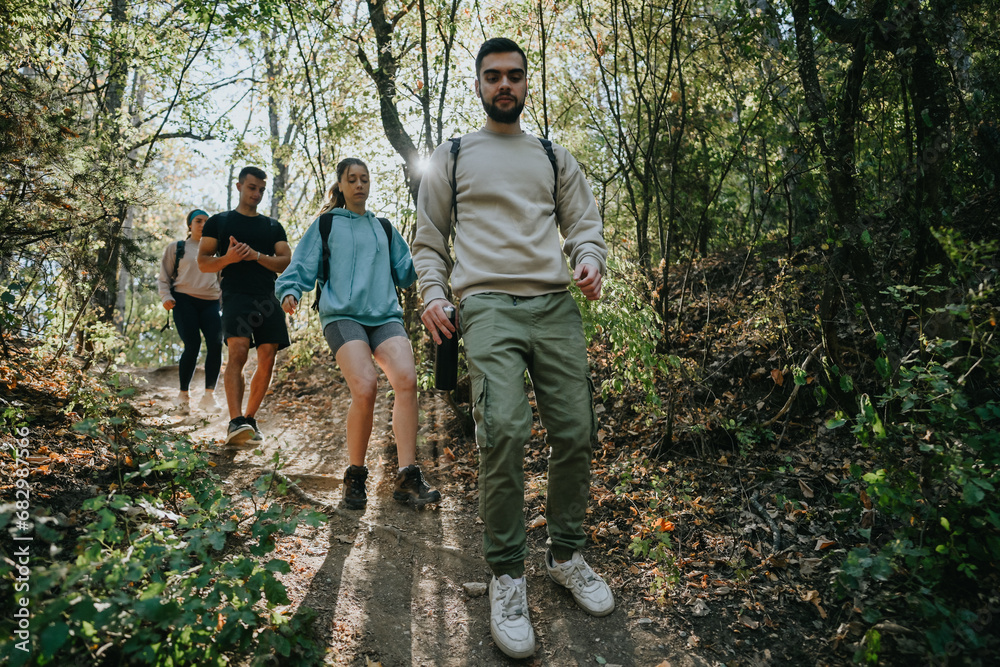 Happy friends enjoying an adventurous hike through a scenic forest, surrounded by natures beauty. They engage in lively conversations while exploring the green environment and taking in the fresh air. Happy friends enjoying an adventurous hike through a scenic forest, surrounded by natures beauty. They engage in lively conversations while exploring the green environment and taking in the fresh air.