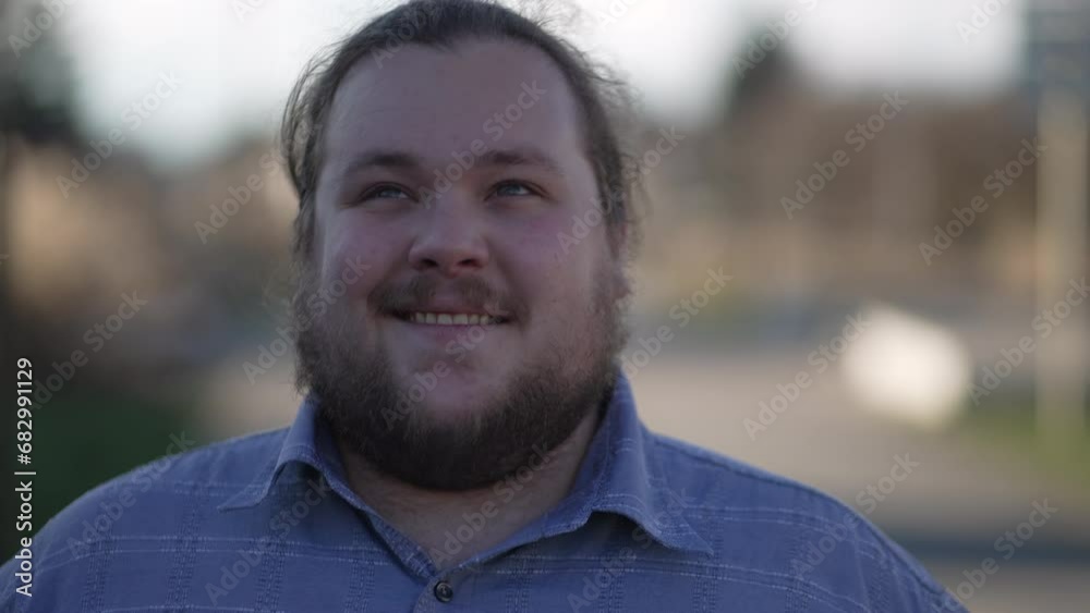 One contemplative young overweight man walking forward outside. Person with meditative expression close up face in movement