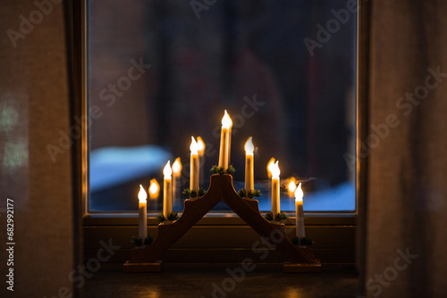 winter holidays and celebration concept - advent candlestick on window sill a...