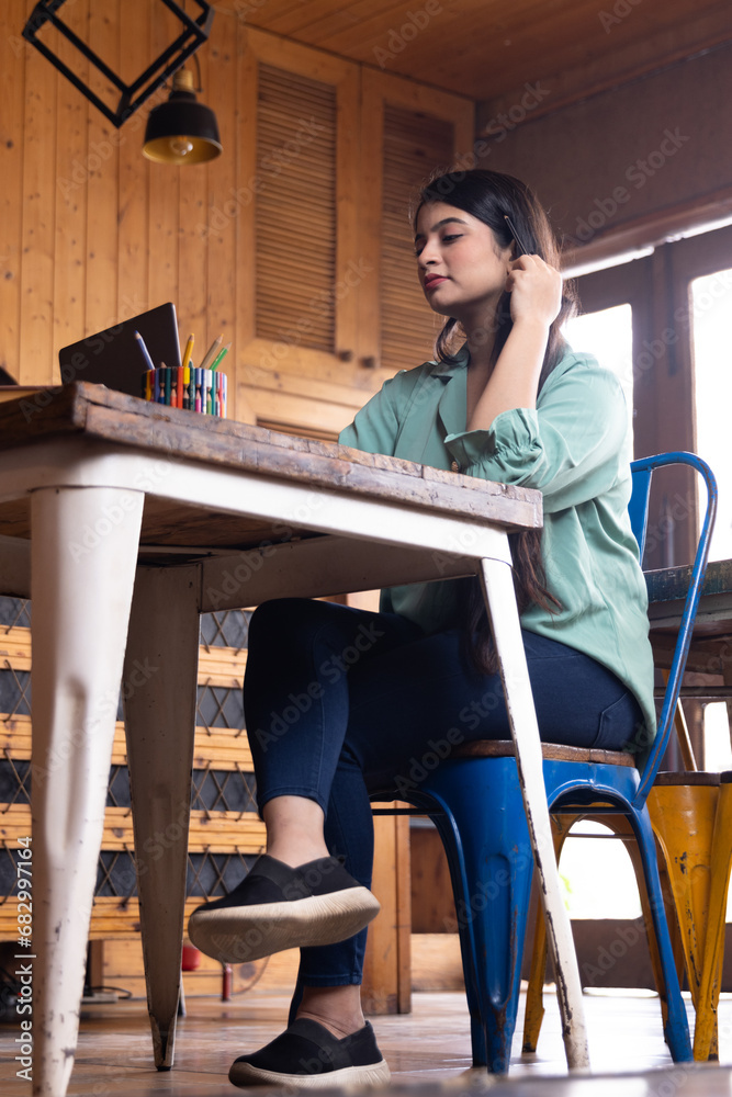 A young business woman or girl or student working or studying in school or collage library cafe or in corporate office using laptop