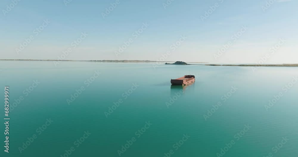 Empty red freight barge anchored in clear calm large reservoir lake. Aerial drone view at summer sunny sunset Empty red freight barge anchored in clear calm large reservoir lake. Aerial drone view at summer sunny sunset