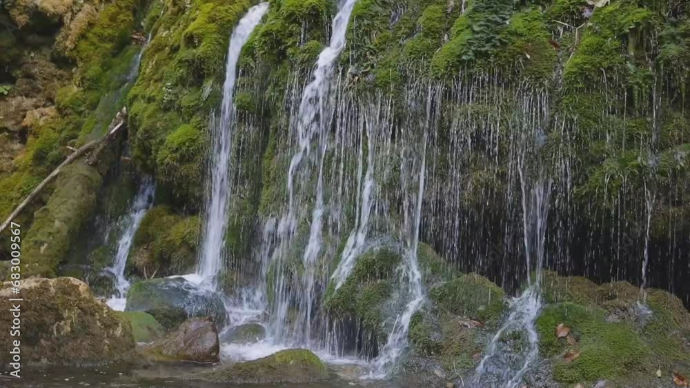 Look up at the gorge, from whose battlemented walls many small waterfalls tumble into the mountain river in the gorge in autumn. Look up at the gorge, from whose battlemented walls many small waterfalls tumble into the mountain river in the gorge in autumn.