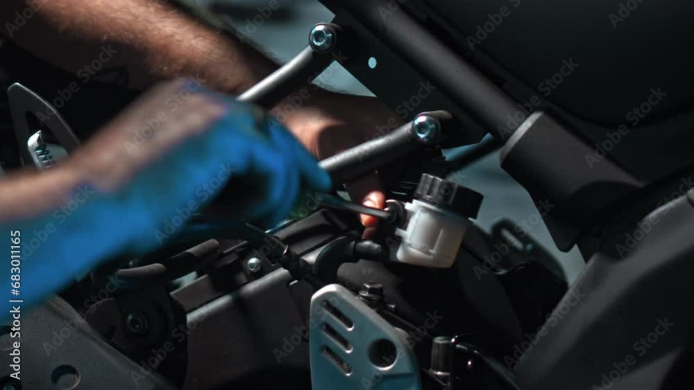 Men's hands repair motorbike in dark workshop